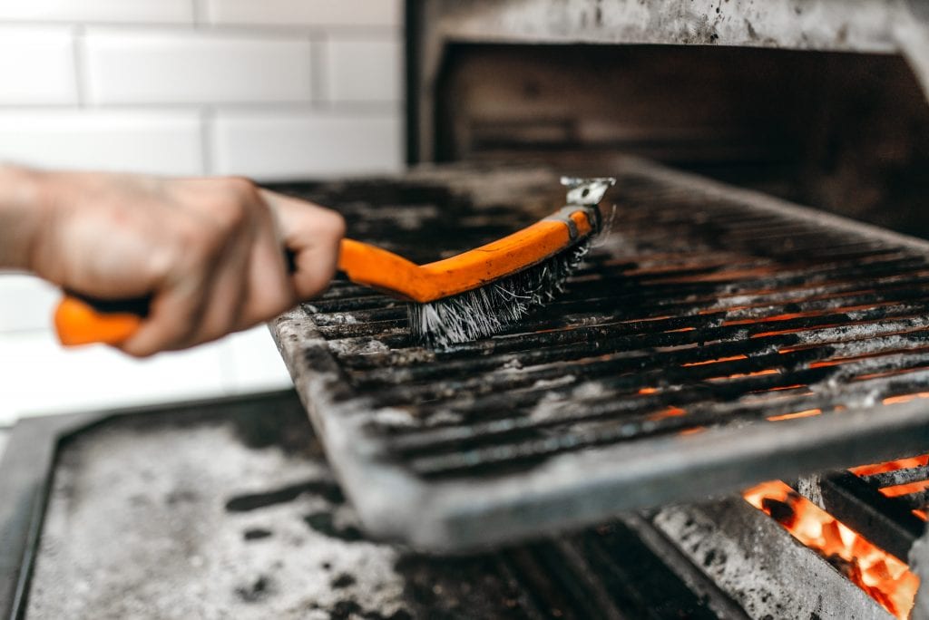 Cook hands with metal brush clean the grill oven