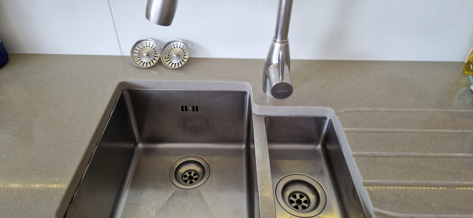 Clean stainless steel sink and tap on a kitchen worktop
