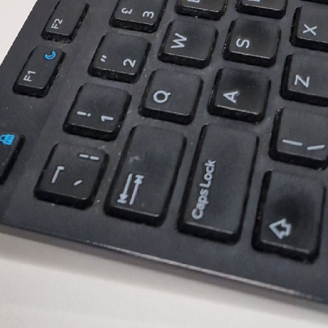 Office keyboard before cleaning, with dust and crumbs between the keys