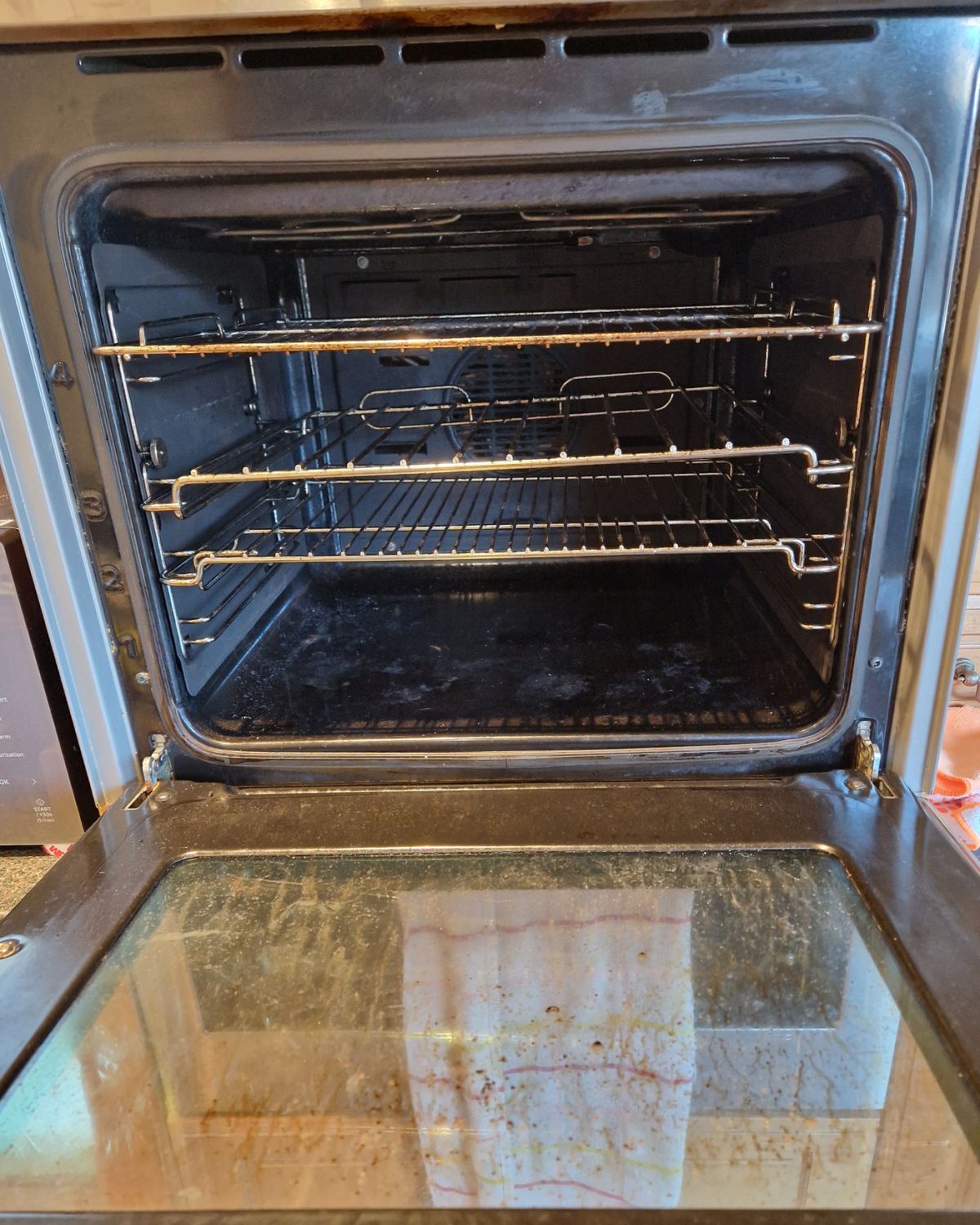 The same oven before cleaning, with grease on the racks, the floor and the door glass