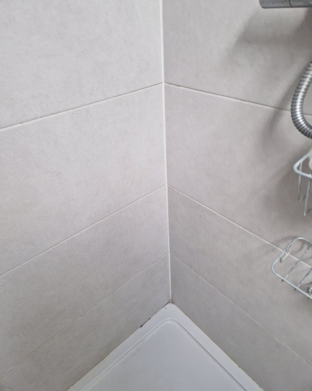 The same shower corner after cleaning, with clean grout and tiles